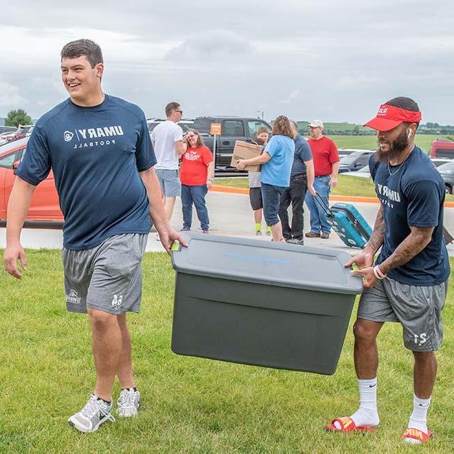 University of Mary football players carrying a tote for new students on campus.